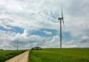 white wind turbine on green grass field under white clouds and blue sky